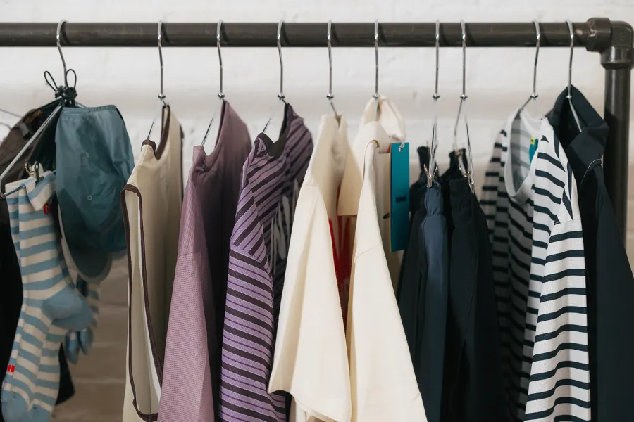Close view of a rack of striped and cream running tops on wire hangers