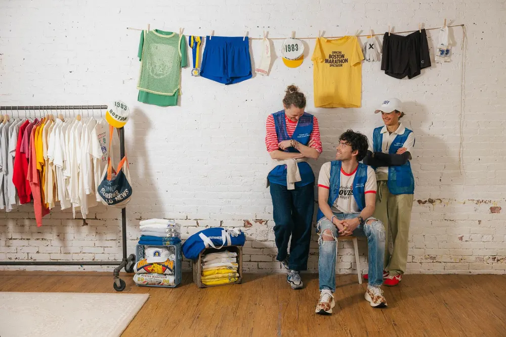 Katherine, Cole, and Lee in staff vests beside a rack of vintage marathon tees at The Rec Room